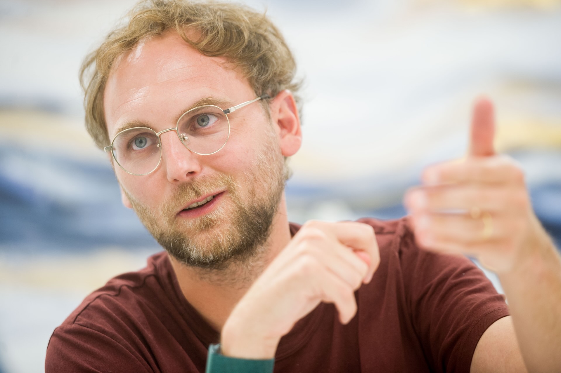 Alan CEO Jean-Charles Samuelian-Werve gestures with his hands while explaining his company’s new AI products. He wears a maroon-coloured shirt and a green watch.
