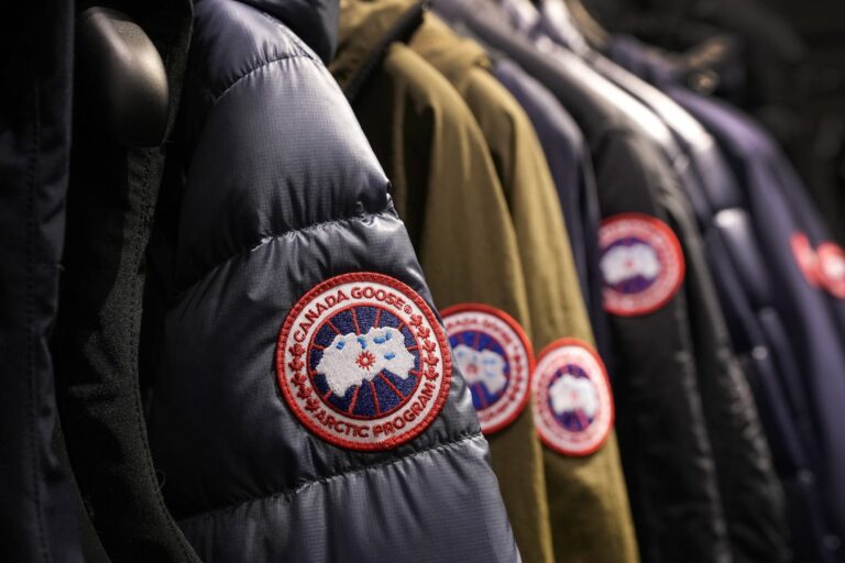 A rack of winter jackets with the Canada Goose arm patch logo visible on each one