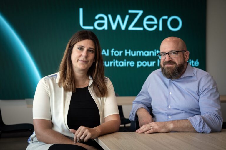 A shot of Catherine Saine and Sam Ramadori seated at a table in front of screen with LawZero's logo on it.