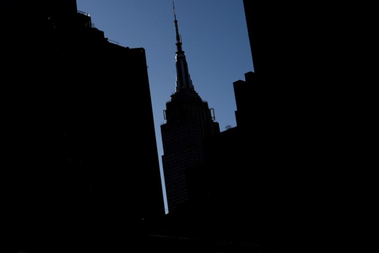 A silhouette of the Empire State Building against a blue sky.