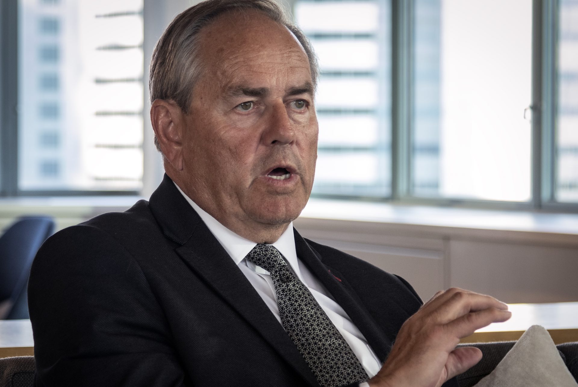 A close-up of Tim Gitzel taken while he's speaking. He is wearing a dark suit jacket, white shirt and patterned tie.